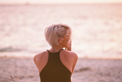 A woman who wears a black condole belt, head towards the beach
